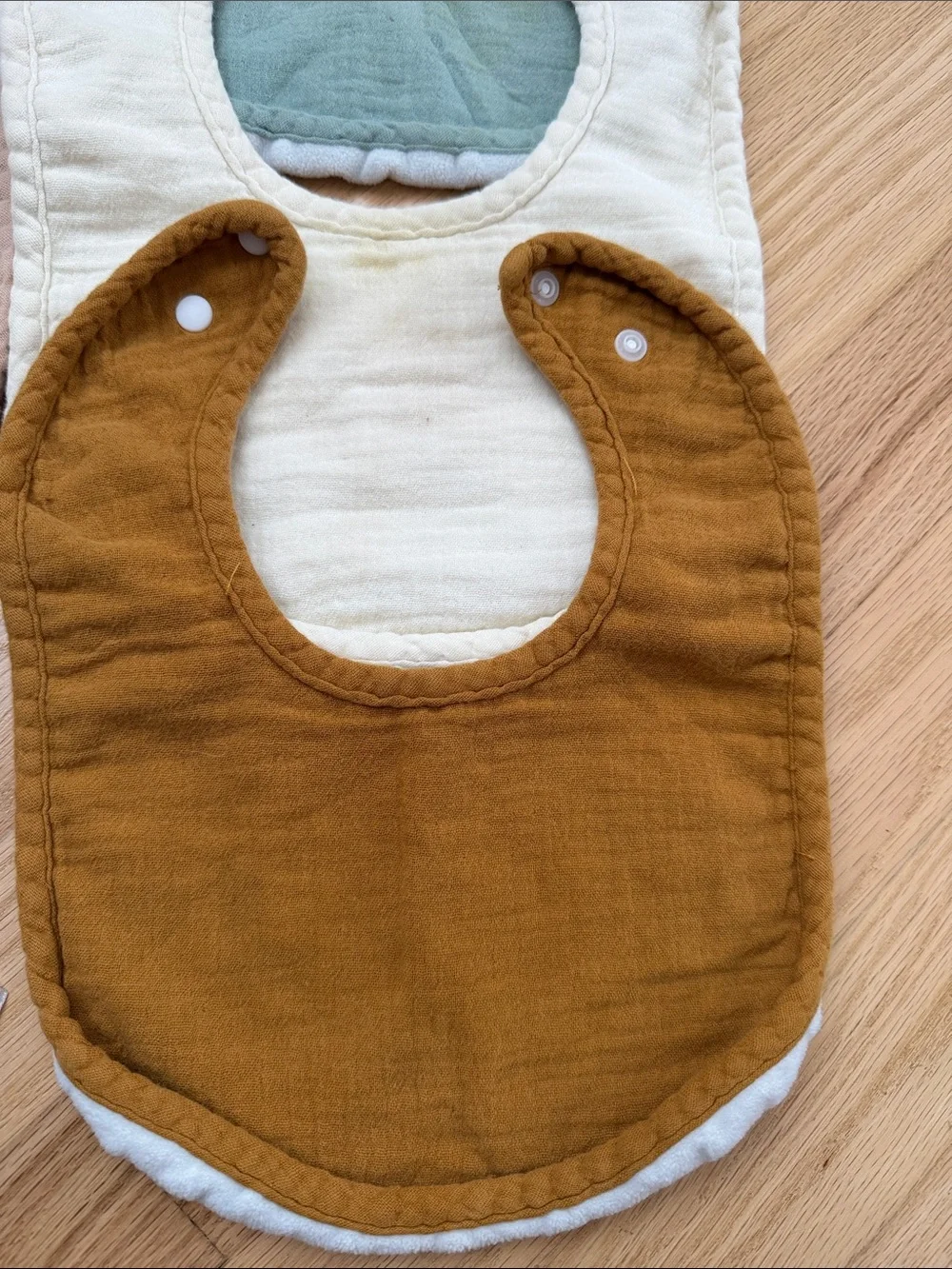 Bundle of muslin baby bibs in earthy colors